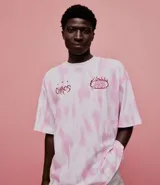 Remera oversized de algodón con teñido tie-dye en blanco y rosa. Presenta un cuello redondo y un estampado frontal con la palabra "Chaos" y un diseño de llamas en color rosado.