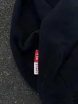 Hoodie de color negro con diseño de estampa frontal que combina una tipografía manuscrita con el texto ITTAI STARS en letras mayúsculas. Presenta un corte holgado, capucha amplia y bolsillo tipo canguro.