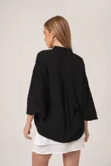 Camisa negra con textura de bolitas, manga globo y cuello camisero.