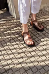 Sandalias de cuero color marrón con apliques de tachas de metal y base forrada en cuero.