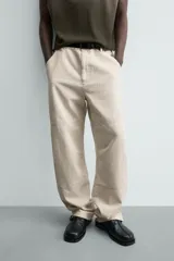 Pantalón relaxed fit color beige, confeccionado en tejido de algodón. Cuenta con bolsillos frontales, bolsillos traseros de plastrón y aplicación de bolsillos plastrón con tira multifunción en la pernera. Cierre frontal con cremallera y botón.