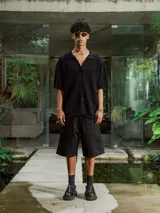 Bermuda negra de gabardina, corte ancho y largo, con bolsillos laterales.