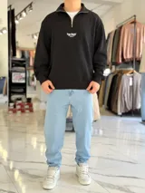 Buzo de felpa color beige con cuello alto, cierre frontal parcial, mangas largas y puños elastizados. Presenta un pequeño estampado en el pecho con la leyenda 'Top Style' y texto secundario.