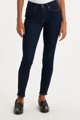 Jeans skinny de tiro medio color azul oscuro, ajustados en cadera y muslos, con cierre de bragueta.