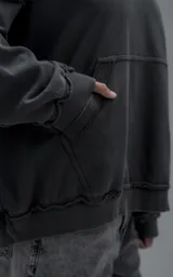 Hoodie oversize de algodón con efecto desgastado, costuras expuestas y roturas decorativas. Presenta capucha, bolsillo frontal tipo canguro y terminaciones deshilachadas.