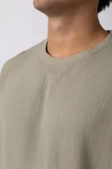 Remera de manga corta con cuello redondo, confeccionada en tejido de lino con textura entramada y corte holgado.