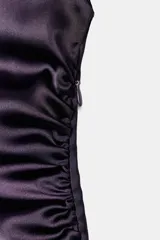 Vestido largo color morado de tejido satinado, sin mangas, con cuello fluido y detalle de drapeado en el lateral.