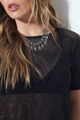 Top de manga corta de tejido mesh (tipo red) color verde militar, con calce relajado y nudo frontal. Se sugiere usar sobre otra prenda debido a su transparencia.