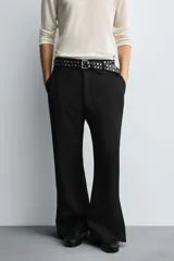 Pantalón de vestir gris oscuro, corte ancho (flare fit) y tiro alto, con bolsillos laterales y falsos bolsillos de vivo en la parte trasera. Presenta un cierre frontal con cremallera y gancho oculto, y botones a presión ocultos en el bajo.