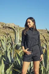 Conjunto de dos piezas compuesto por un polerón de cuello alto y manga larga, y un short de tiro alto, ambos en color negro con estampado de rayas verticales blancas.