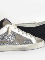 Zapatillas bajas Golden Goose modelo Super-Star, con glitter plateado, estrella de gamuza gris y detalles en cuero blanco.