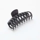 Pack de dos pinzas para el pelo, una con forma de espiral y otra rectangular con diseño calado, ambas de color negro.