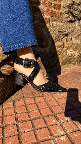 Zapatos de tacón ancho color camel con textura símil serpiente, punta fina y tiras cruzadas con hebilla metálica grande en el lateral.