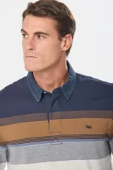 Remera tipo polo de manga larga con diseño de rayas horizontales en tonos azul marino, marrón, gris y blanco. Presenta cuello de tela tipo denim y cierre frontal con botones ocultos.