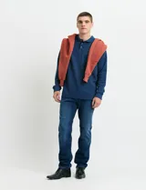 Remera de manga larga con cuello polo, confeccionada en tejido de punto canalé francés. Presenta abotonadura frontal con botones de madera y detalles a contratono en la cartera y el interior del cuello.
