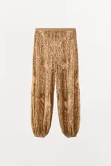 Pantalón de tiro medio con cintura elástica y bajo abullonado. Presenta un diseño con hilo metalizado y aplicaciones de abalorios y lentejuelas en toda la prenda.