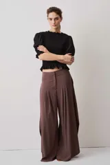 Blusa negra con cuerpo fruncido tipo smock, mangas cortas abullonadas con puños elásticos y volados en el cuello y el ruedo.