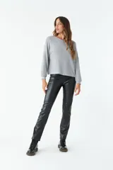 Pantalón negro de cuero sintético, tiro medio y corte recto.