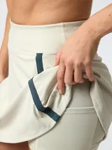 Skort deportivo color beige con detalles de líneas azul marino en los laterales y short interior integrado.