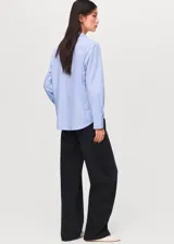 Camisa de rayas celestes y blancas, de manga larga con puños abotonados, corte recto, cuello camisero y cierre delantero con botones.
