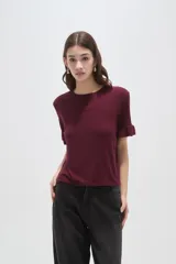 Remera negra de viscosa con textura acanalada, cuello redondo y mangas cortas terminadas en volados.