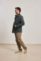 Campera verde militar de algodón y elastano, con cierre frontal de botones y cremallera, cuatro bolsillos delanteros con solapa y cordón ajustable en la cintura. Forro interior de viyela de algodón a cuadros.