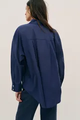 Camisa de corte amplio confeccionada en algodón, con cuello solapa, manga larga, bolsillo delantero de plastrón y cierre frontal con botones.