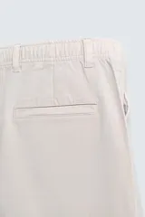 Pantalón de corte recto confeccionado en tejido de sarga con estructura diagonal. Presenta cintura elástica, bolsillos delanteros, bolsillos traseros de vivo y cierre frontal con cremallera y botón.