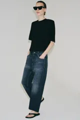 Jeans de tiro bajo con corte loose leg y largo tobillero. Presenta diseño de cinco bolsillos, cierre frontal con cremallera y botón, y acabado con efecto lavado.