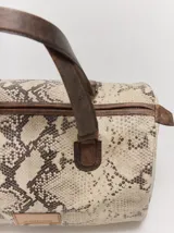 Cartera tipo baúl Margara Shaw confeccionada en 100% cuero con estampado animal print de serpiente, asas de mano marrones y cierre superior.