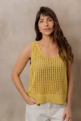 Chaleco tejido calado de color amarillo, con escote redondo, tirantes anchos y calce relajado. Cuenta con terminaciones en rib en el ruedo.