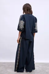 Blusa azul marino con cuello mao, mangas 3/4 abullonadas y bordados en color crema en hombros y mangas.