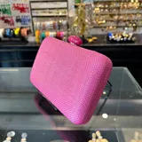 Clutch rectangular rígido de rafia sintética color fucsia, con cierre a tono y asa desmontable de cadena dorada para llevar al hombro.