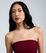 Blusa peplum sin tirantes de color negro, confeccionada en bengalina con diseño asimétrico en el dobladillo.