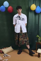 Falda midi de corte amplio con cintura elastizada y frunces laterales, confeccionada en tejido tipo gobelino con estampado floral sobre fondo azul.