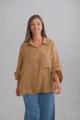 Camisa de lino italiano color tostado, con corte oversize, cuello clásico, cierre frontal con botones y mangas largas con puños elásticos.