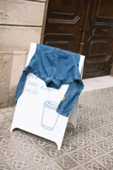 Camisa de jean estilo oversize con cuello camisero, cierre frontal con botones y mangas largas con puños. Presenta un diseño de denim clásico con costuras visibles.