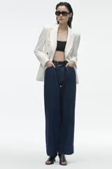 Blazer de corte entallado con cuello y solapa, manga larga y hombros marcados. Presenta un cierre frontal cruzado con botones dorados y bolsillos delanteros con solapa.