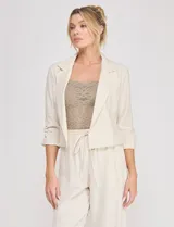 Blazer corto de lino color beige, marca Allie Rose, de estilo relajado y corte crop con frente abierto sin botones. Presenta solapa de muesca y mangas tres cuartos con detalle fruncido en los laterales.