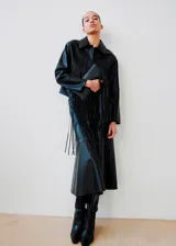 Chaqueta de cuero sintético negro con solapas clásicas, cierre frontal de botones ocultos y mangas largas amplias.