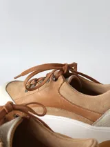 Zapatillas deportivas de cuero color camel con cordones marrones y suela blanca.