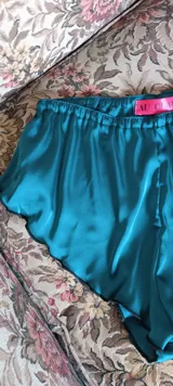 Mini culotte color verde esmeralda confeccionado en satén dull, con cintura elástica y terminaciones con puntilla negra.