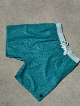 Short de baño turquesa con estampado de figuras geométricas y cintura elástica con cordón ajustable.