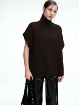 Chaleco tipo poncho de tejido de punto grueso, color marrón, con cuello alto tipo polera y diseño holgado con laterales abiertos.