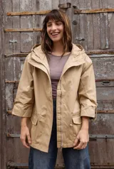 Parka liviana color beige con capucha, cierre frontal con cremallera, bolsillos delanteros con tapa y mangas tres cuartos con ajuste. Cuenta con cordón interno para ajustar la cintura.