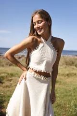 Top halter amarillo pálido de lino, con tiras cruzadas y terminación de mini ojalillos en el escote.