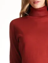 Polera de tejido fino, color rosado, con cuello alto, manga larga y detalle de tajo en los puños.