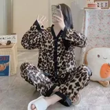 Conjunto de pijama de dos piezas compuesto por una camisa de manga larga con cuello mao y cierre frontal de botones, y un pantalón largo. Presenta un diseño estampado de corazones sobre fondo negro con detalles en color blanco.