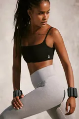 Top deportivo blanco, tipo bralette, con escote cuadrado y tirantes finos. Presenta tejido acanalado y diseño sin costuras.