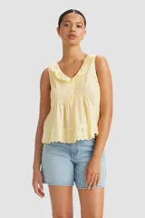 Blusa amarilla sin mangas con cuello con volados y cierre frontal con botones.